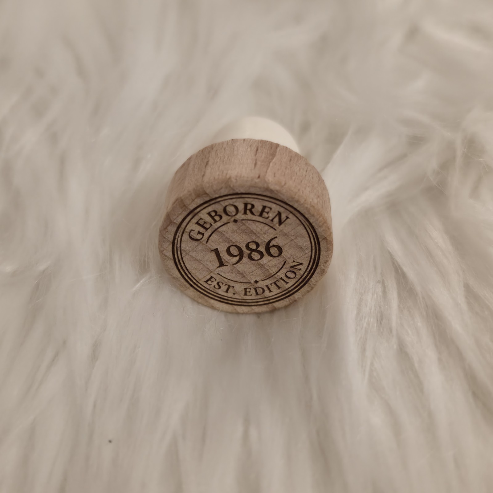 Flaschenstopfen Holz mit Gravur "Geboren 1986 EST Edition" auf weißem, flauschigem Untergrund, personalisierbar